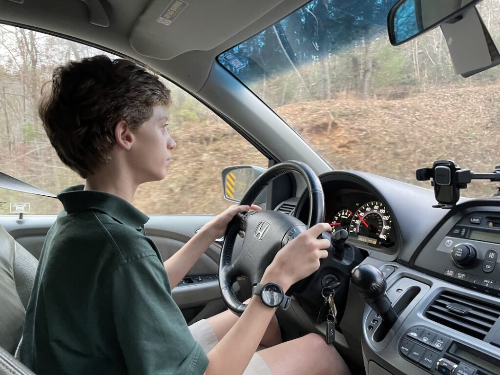 My oldest son driving our Honda Odyssey minivan. He's leaning in towards the steering wheel to maximize visibility.